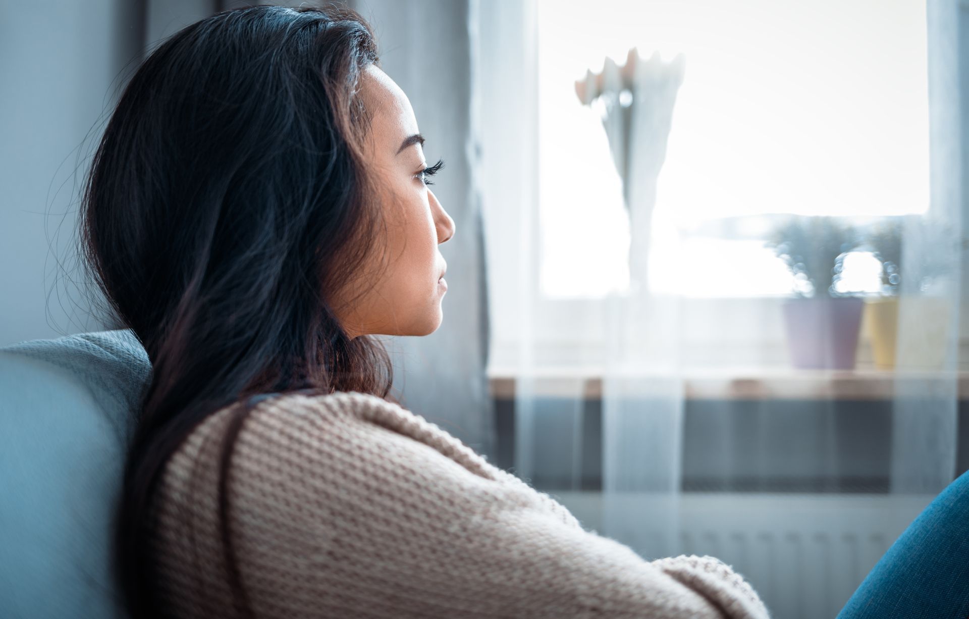 Woman sitting thoughtfully by a window in Fairfax VA representing the emotional weight of a life.