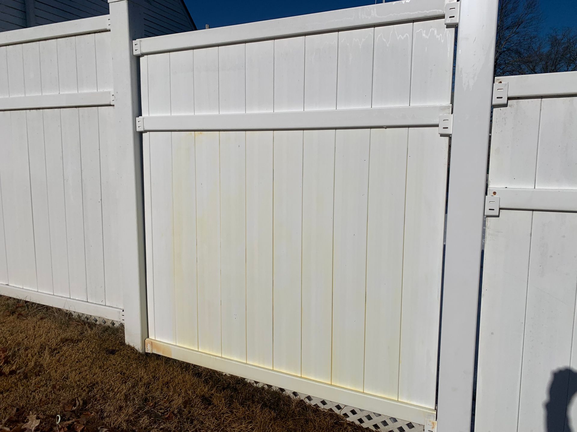 White vinyl fence with yellow stains.