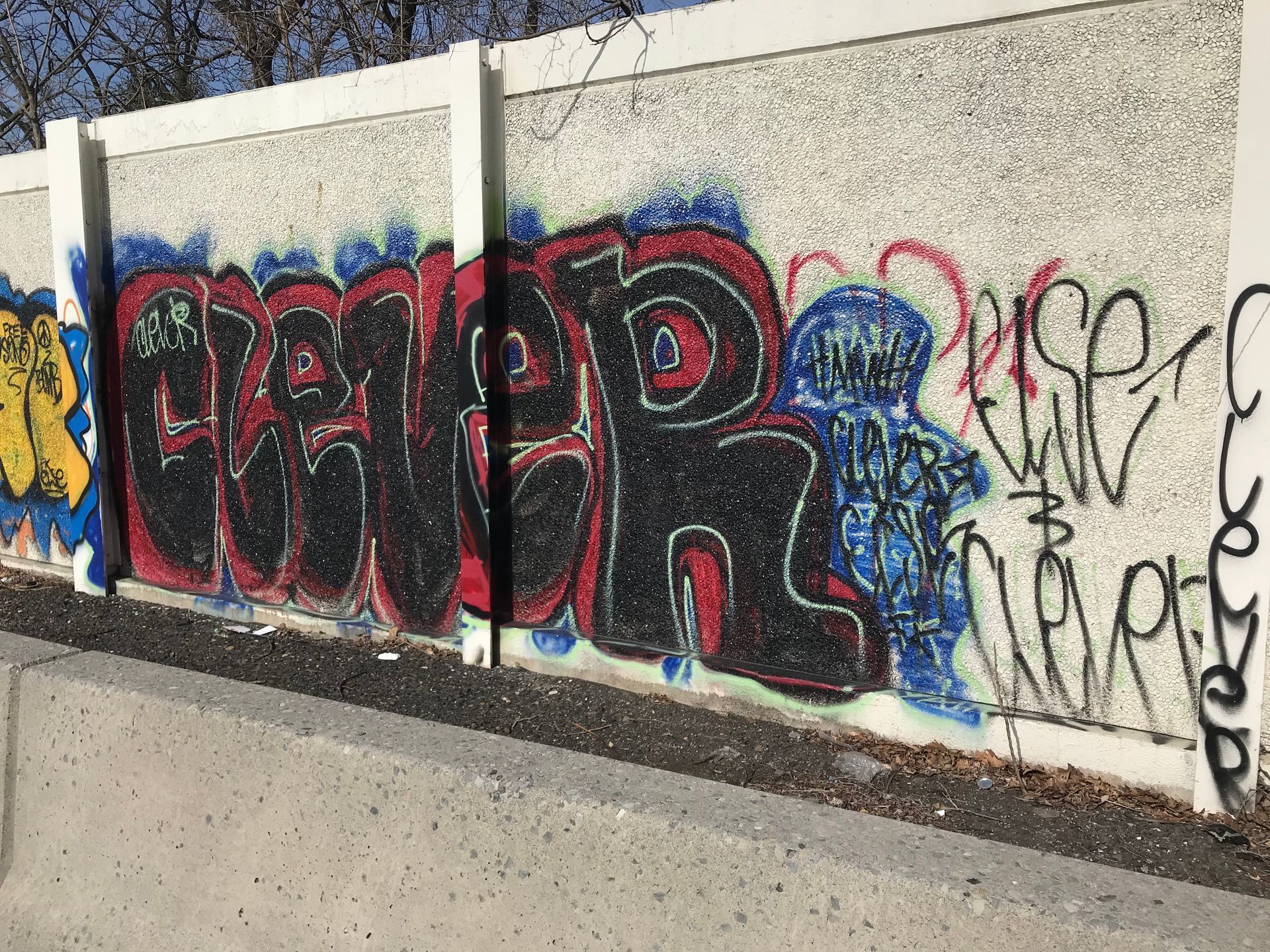 Graffiti on concrete wall; large, black letters with red outline and blue accent.