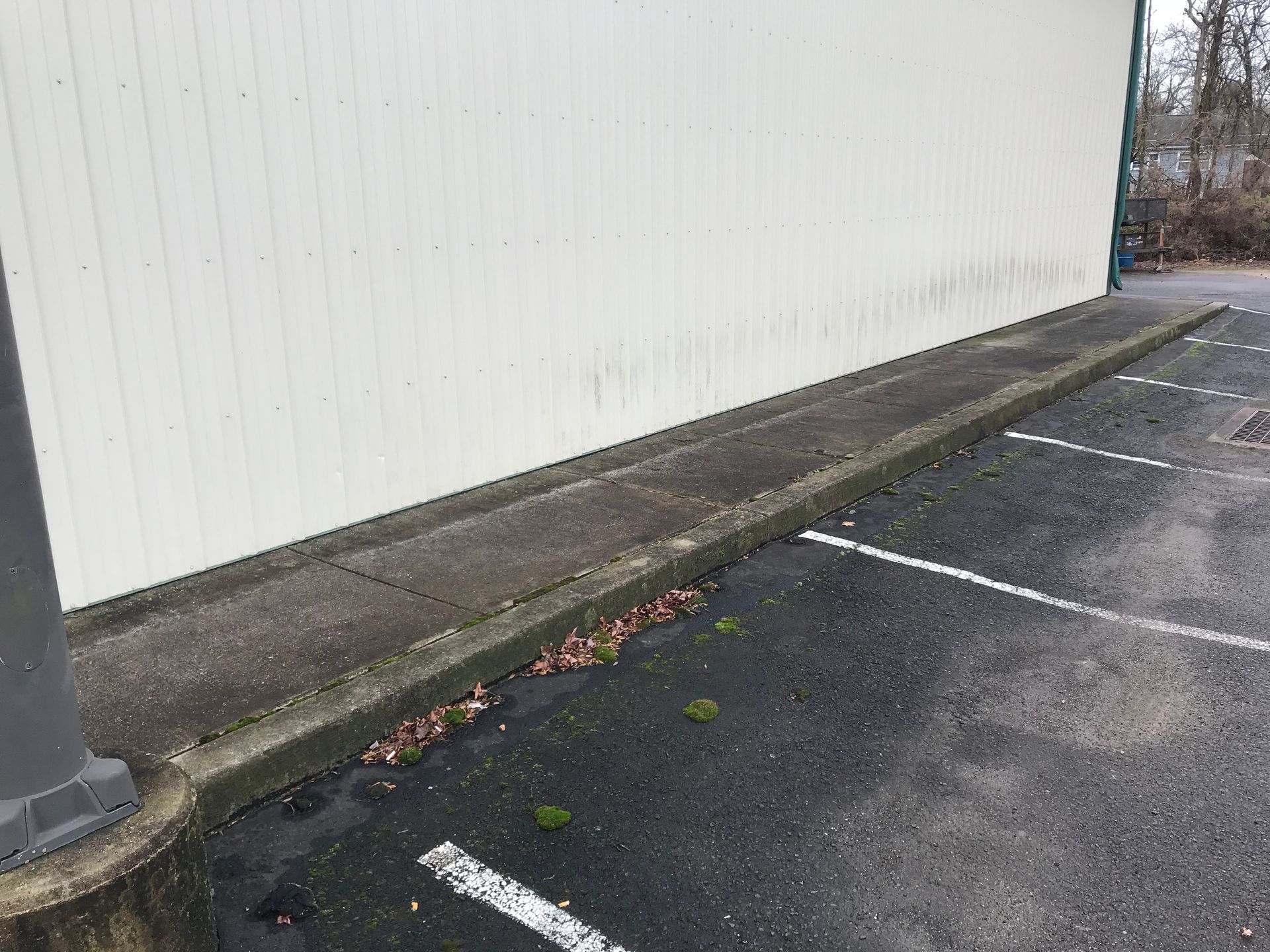 Concrete curb running along a building wall in a parking lot.