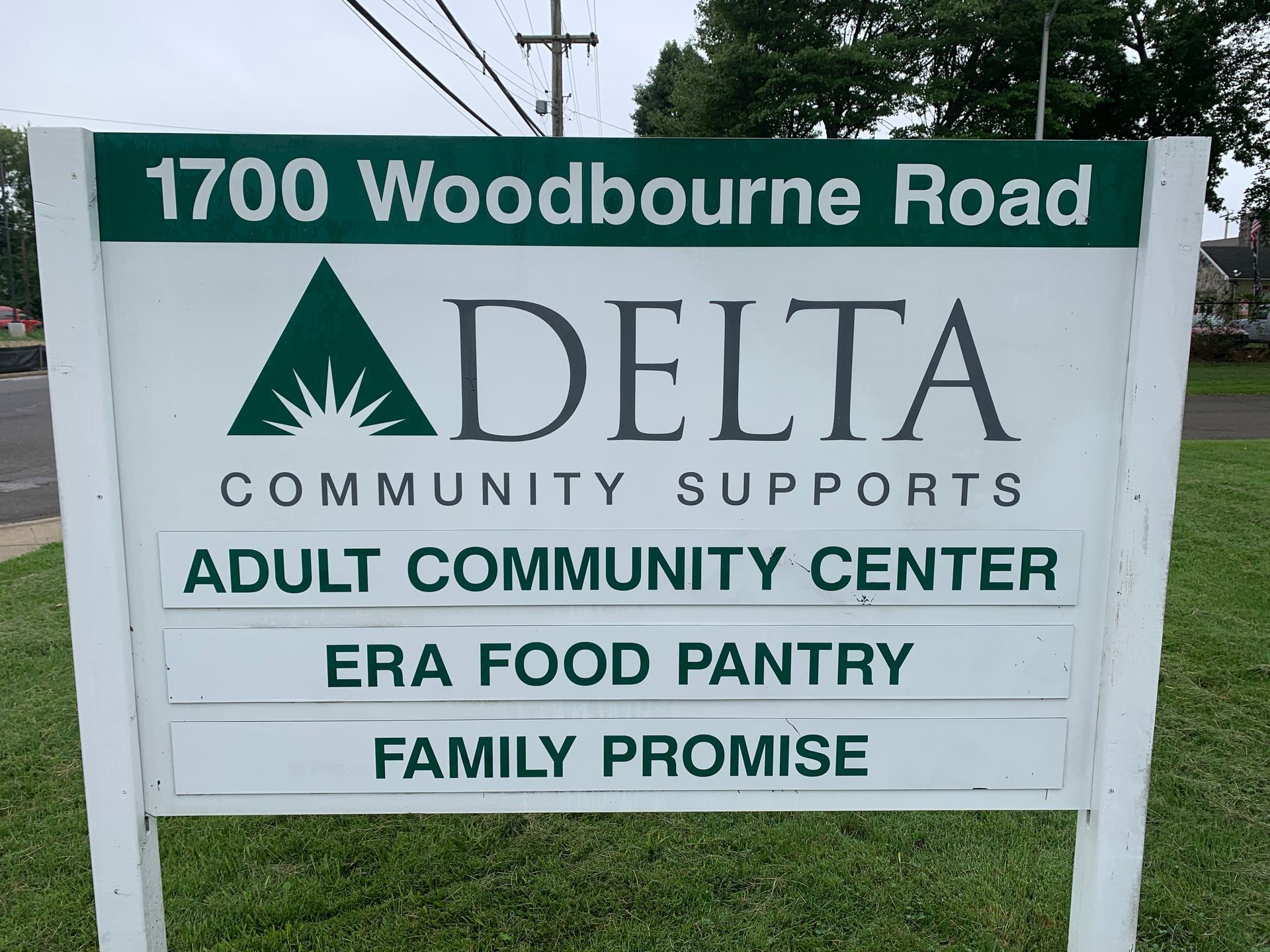 Sign for Delta Community Supports at 1700 Woodbourne Road, listing Adult Community Center, ERA Food Pantry, and Family Promise.
