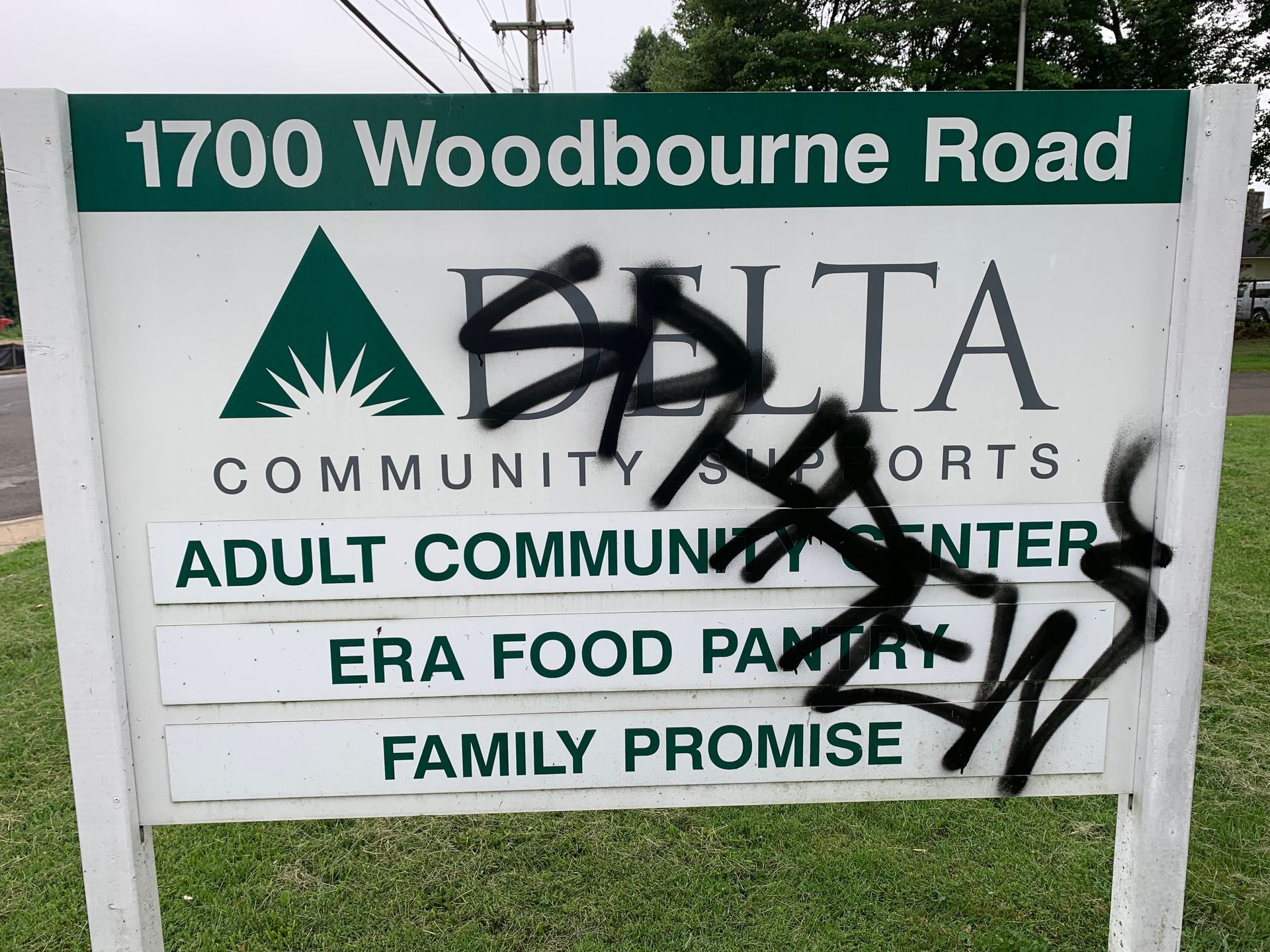 Sign for Delta Community Center defaced with black graffiti; reads 