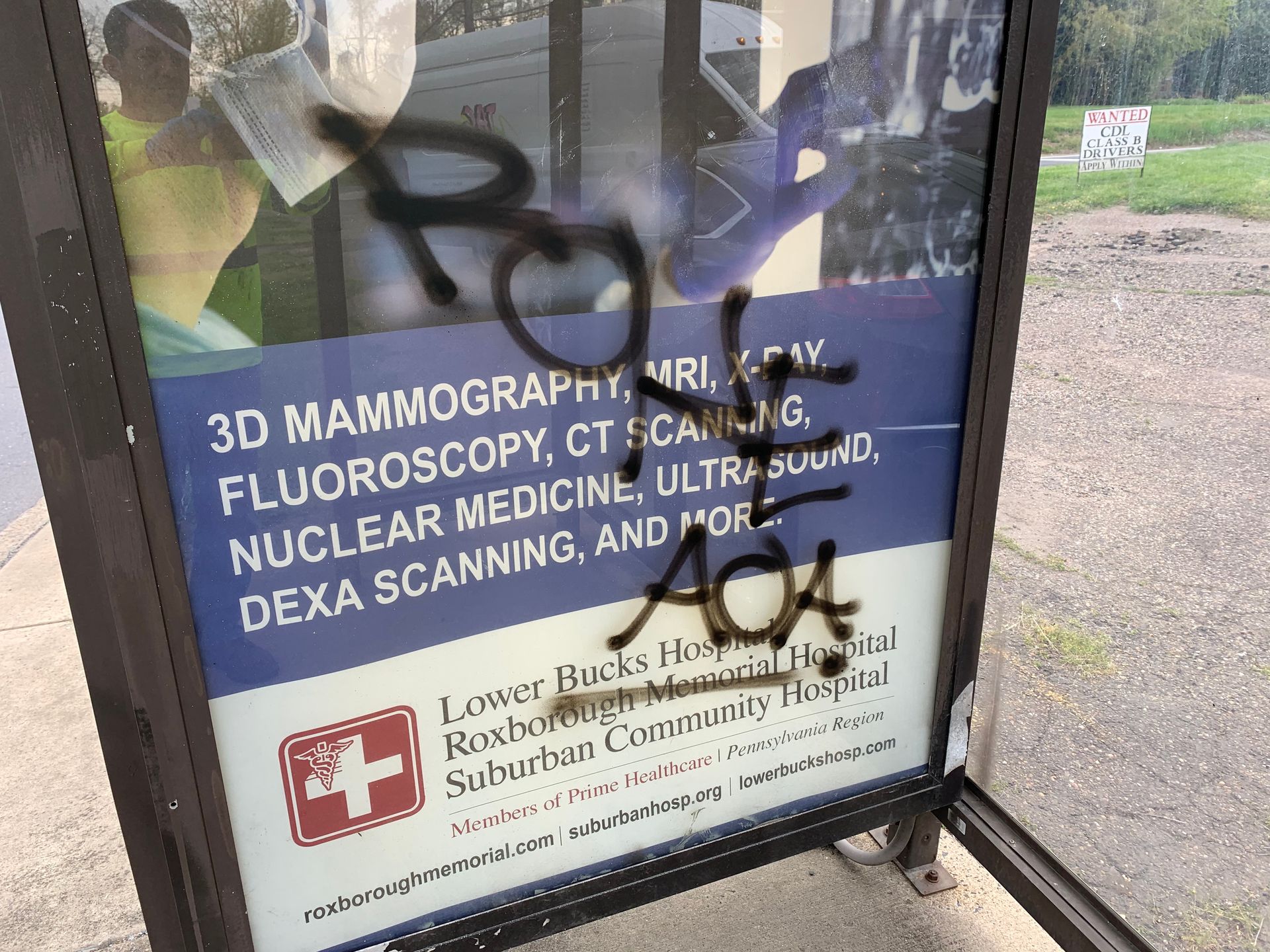 Graffiti on medical advertisement at a bus stop. Text says 