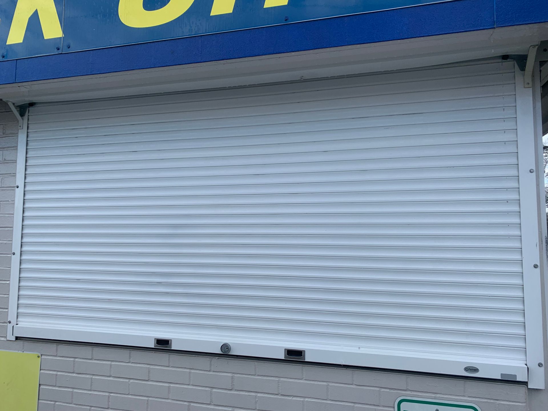 White, closed security shutter on a building exterior.