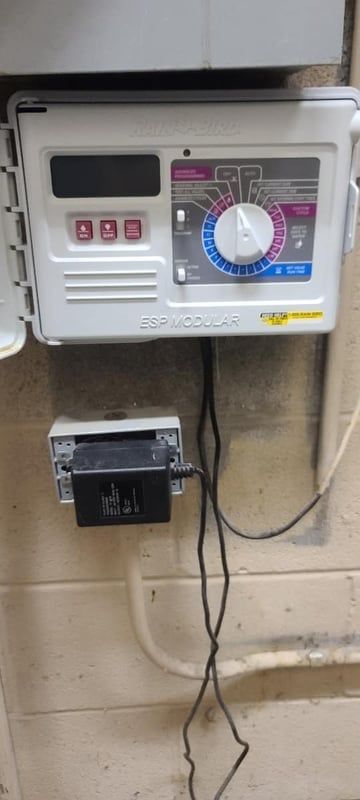 Wall-mounted electric meter and control panel with a blue dial, attached to a beige wall with wires below