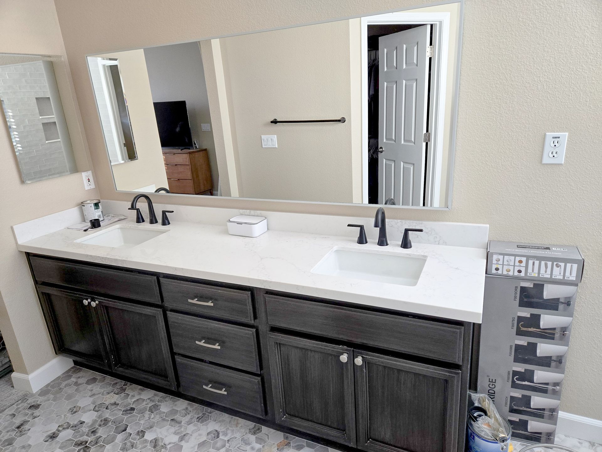 Bathroom with dark cabinets, white countertop, and large mirror.