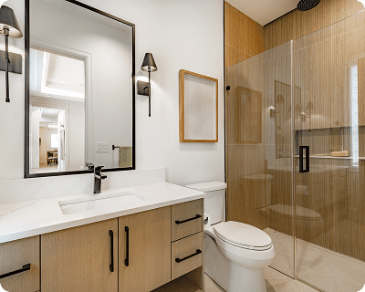 Modern bathroom with a light wood vanity, black fixtures, and a glass shower.