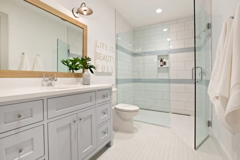 Modern white bathroom with gray vanity, glass shower, and