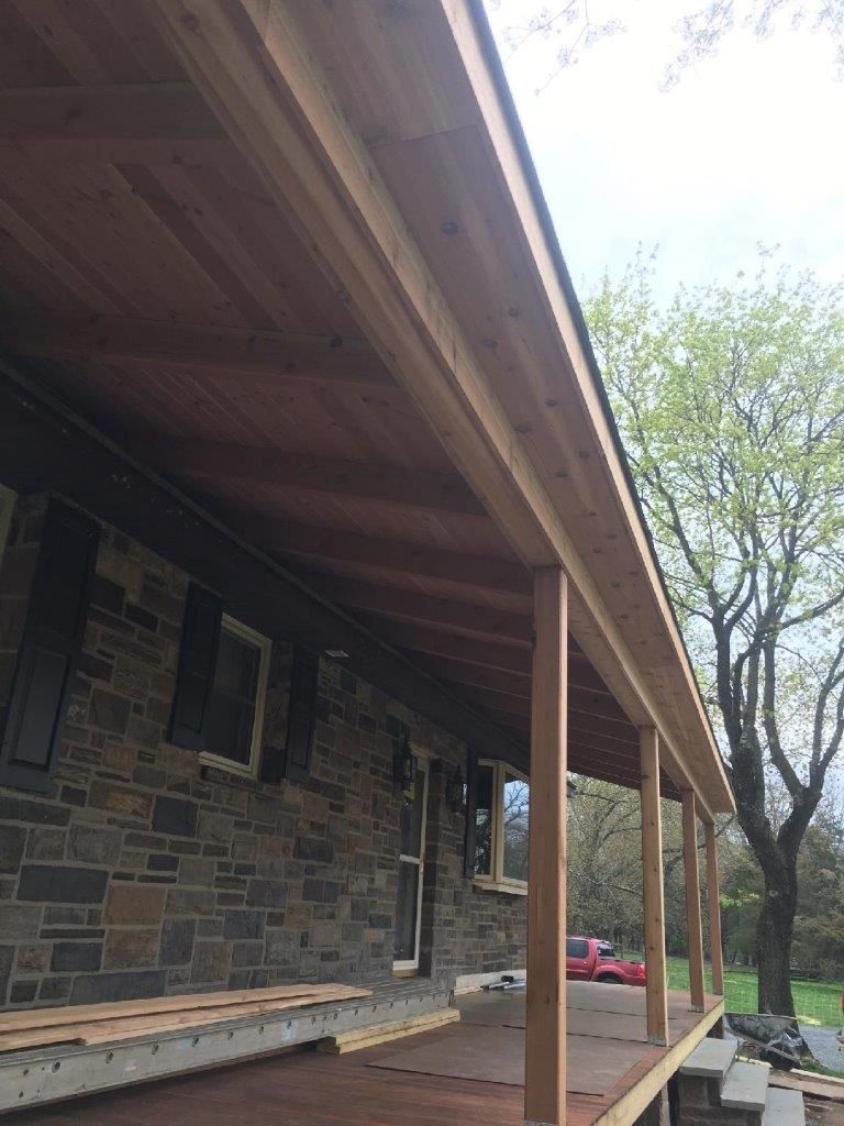 A wooden porch is being built on the side of a brick house.