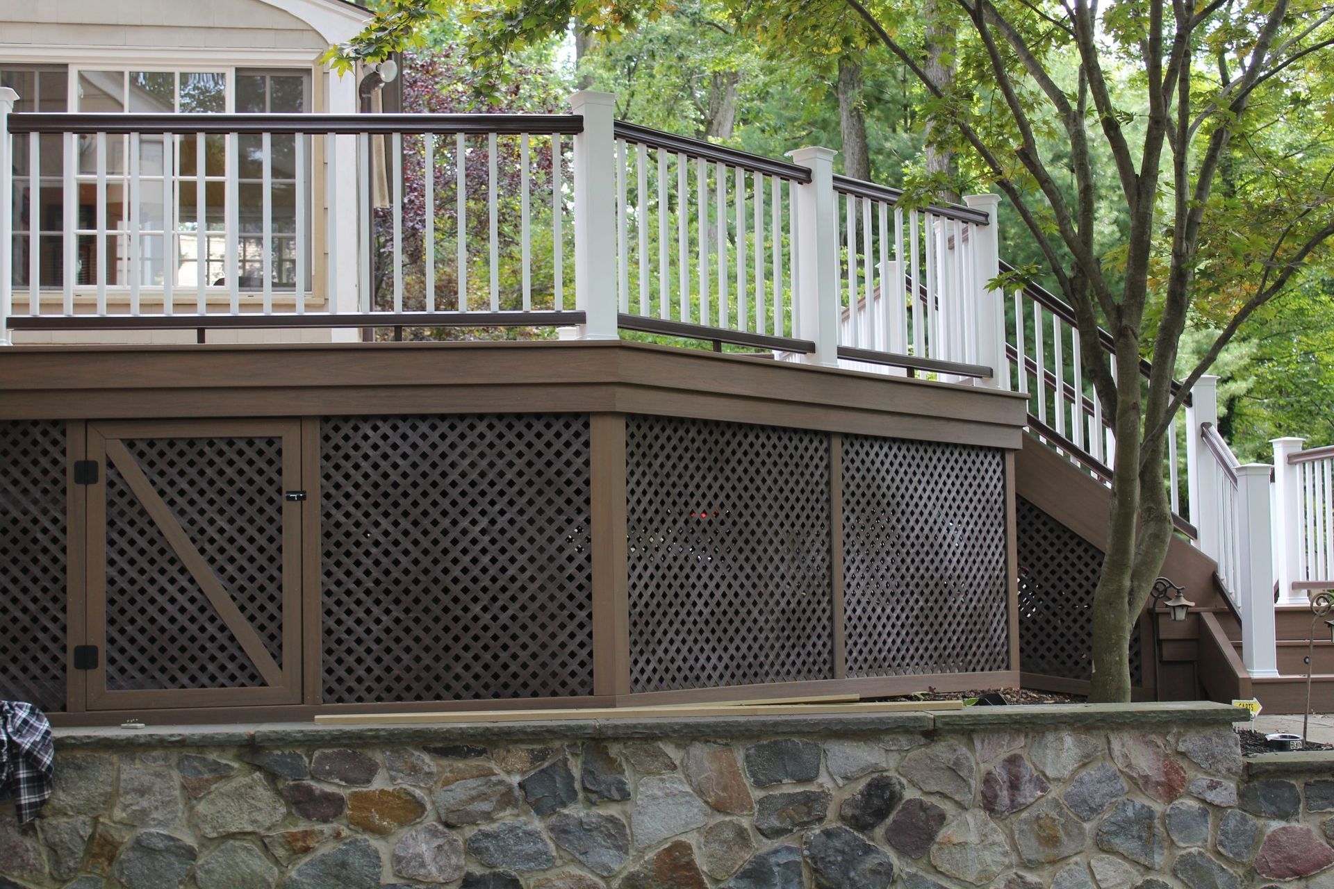 Raised deck with white and brown railings above stone retaining wall by NJ deck experts