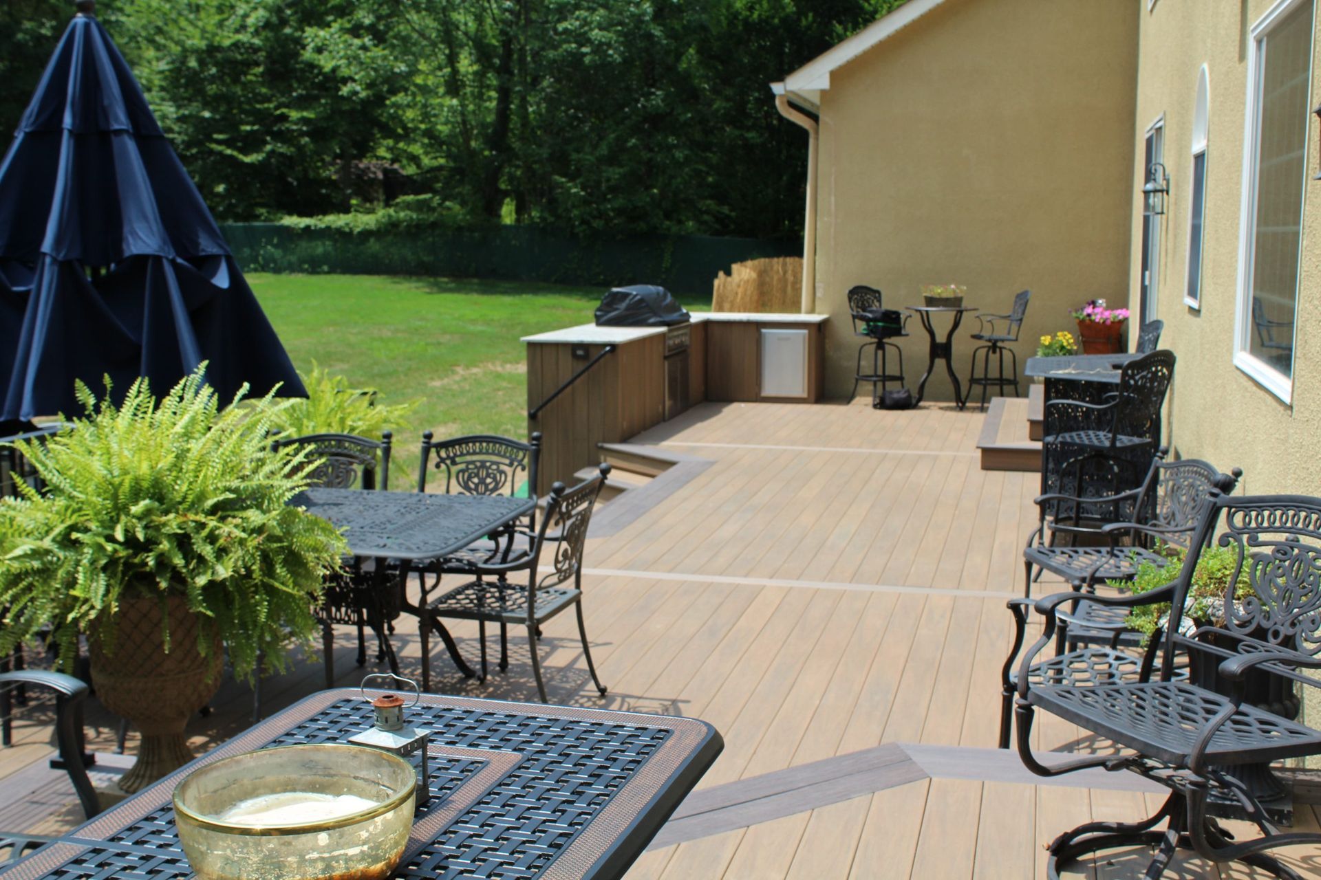 Deck with two-tone railings and steps leading to landscaped backyard built by New Dimensions