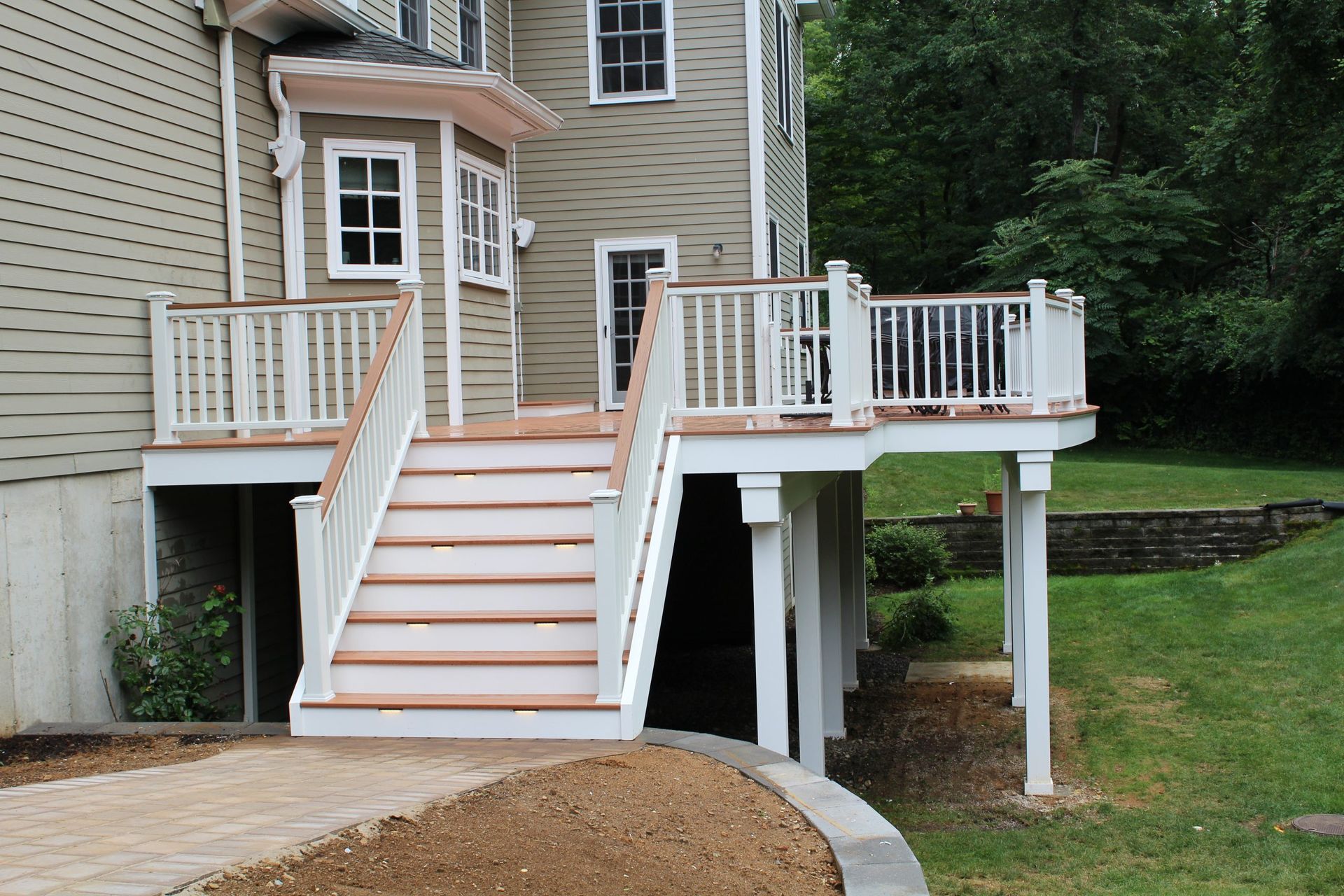 Elevated deck with white railings and stairs leading to backyard.