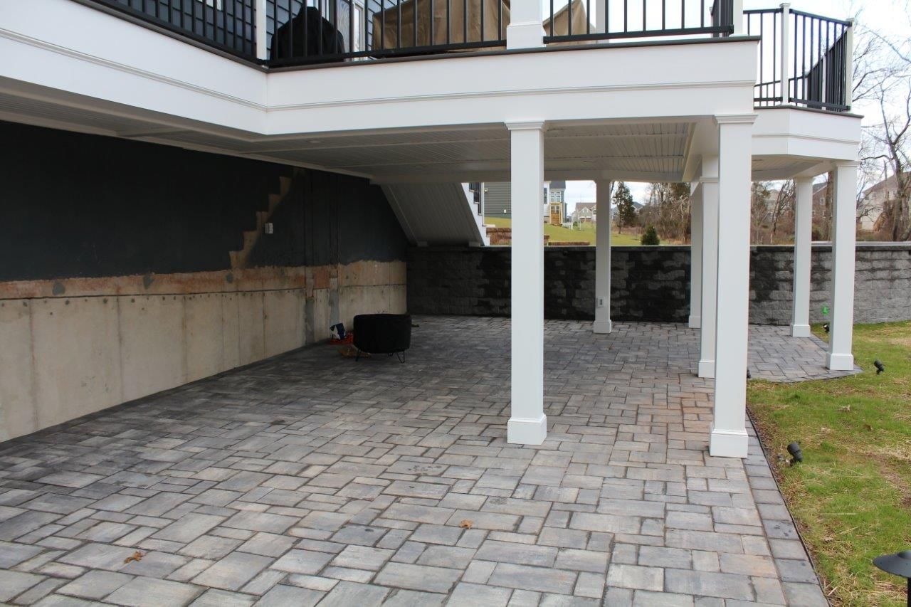 A patio with a balcony and stairs underneath it