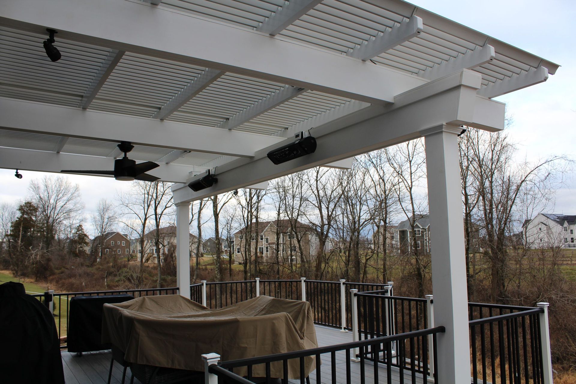 Covered deck with white pergola and ceiling fans.