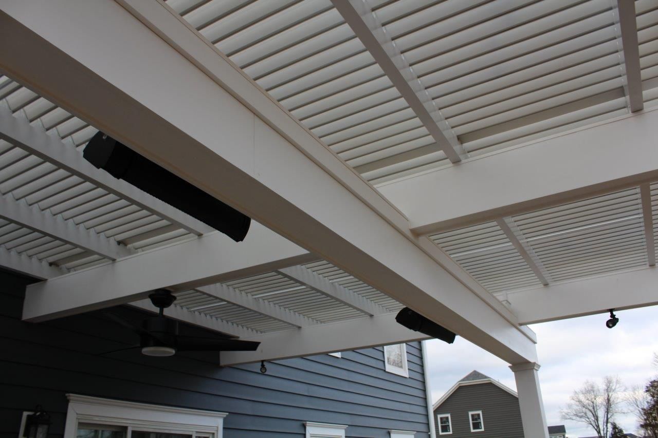A pergola with a ceiling fan and speakers underneath it