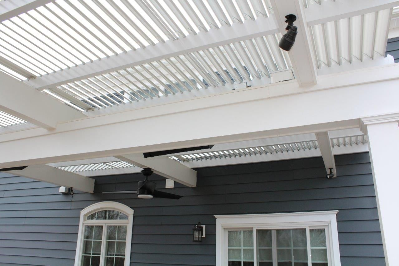 A blue house with a white pergola and a ceiling fan