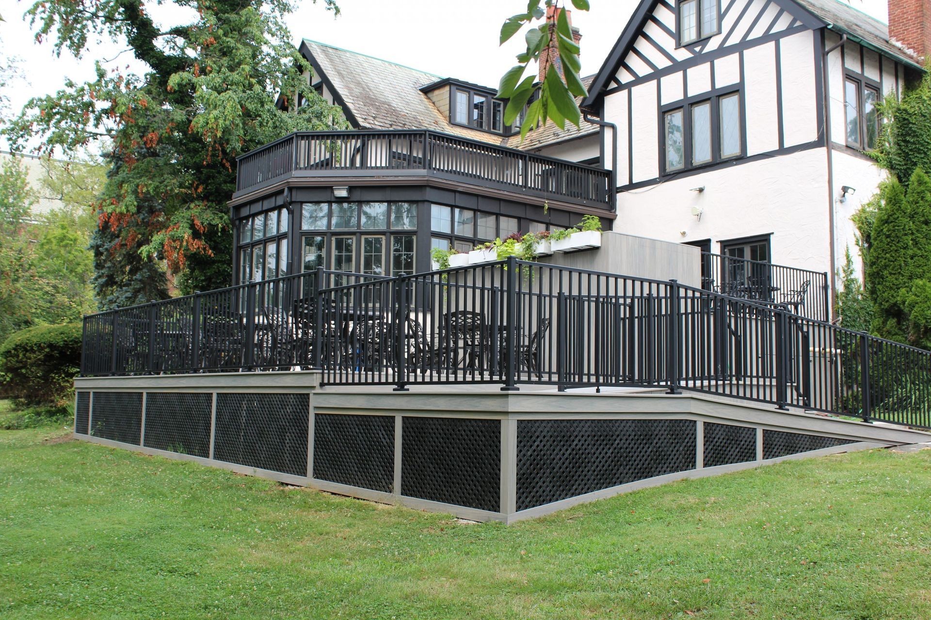 Large black-railed deck on Tudor-style home.