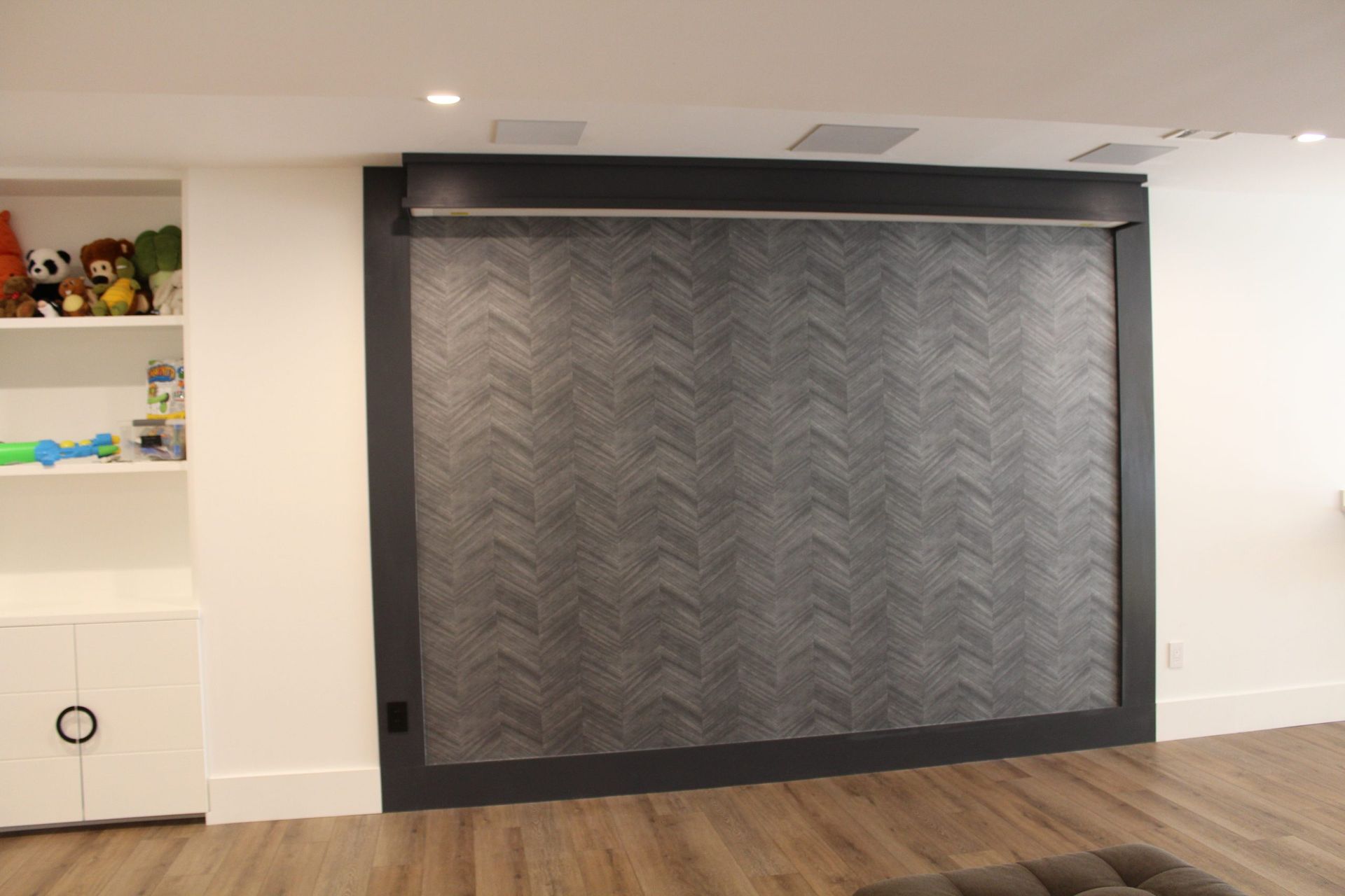 Large gray chevron-pattern feature wall framed in dark trim with wood floors.