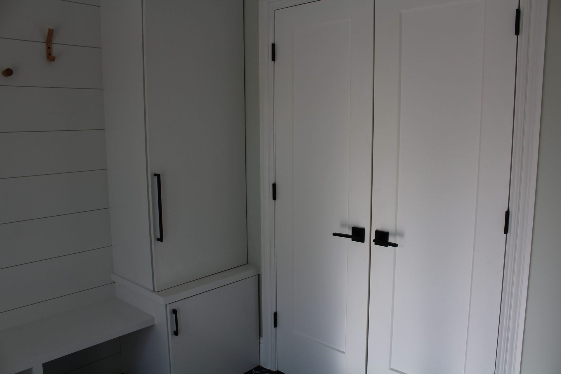A closet with white doors and black handles in a house.