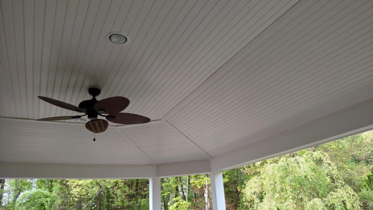 A ceiling fan is hanging from the ceiling of a porch.