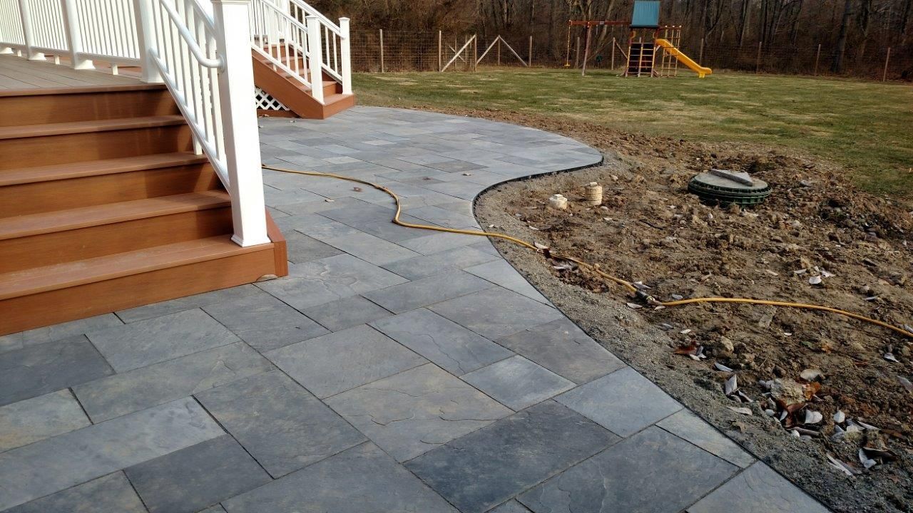 A patio with stairs and a playground in the background.