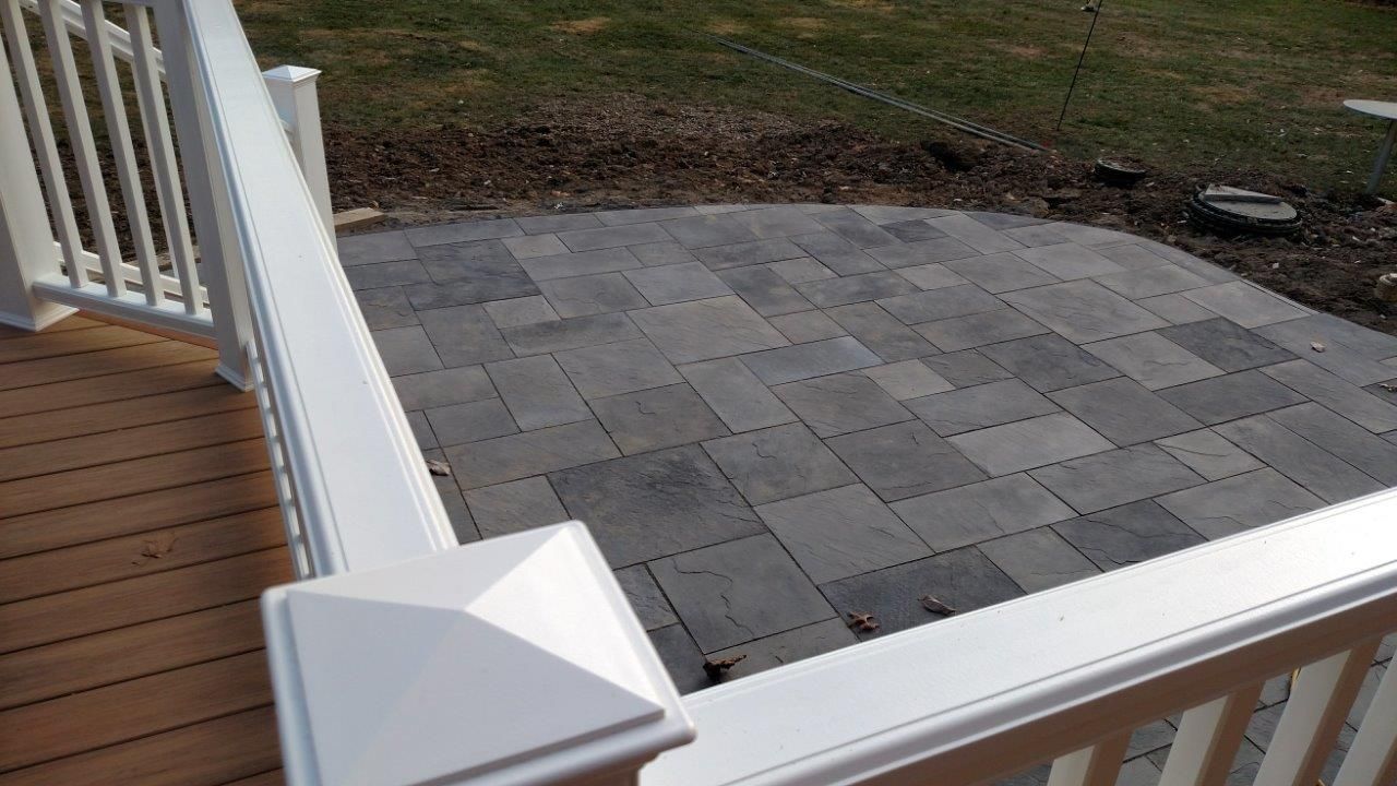 A wooden deck with a white railing and a brick patio.