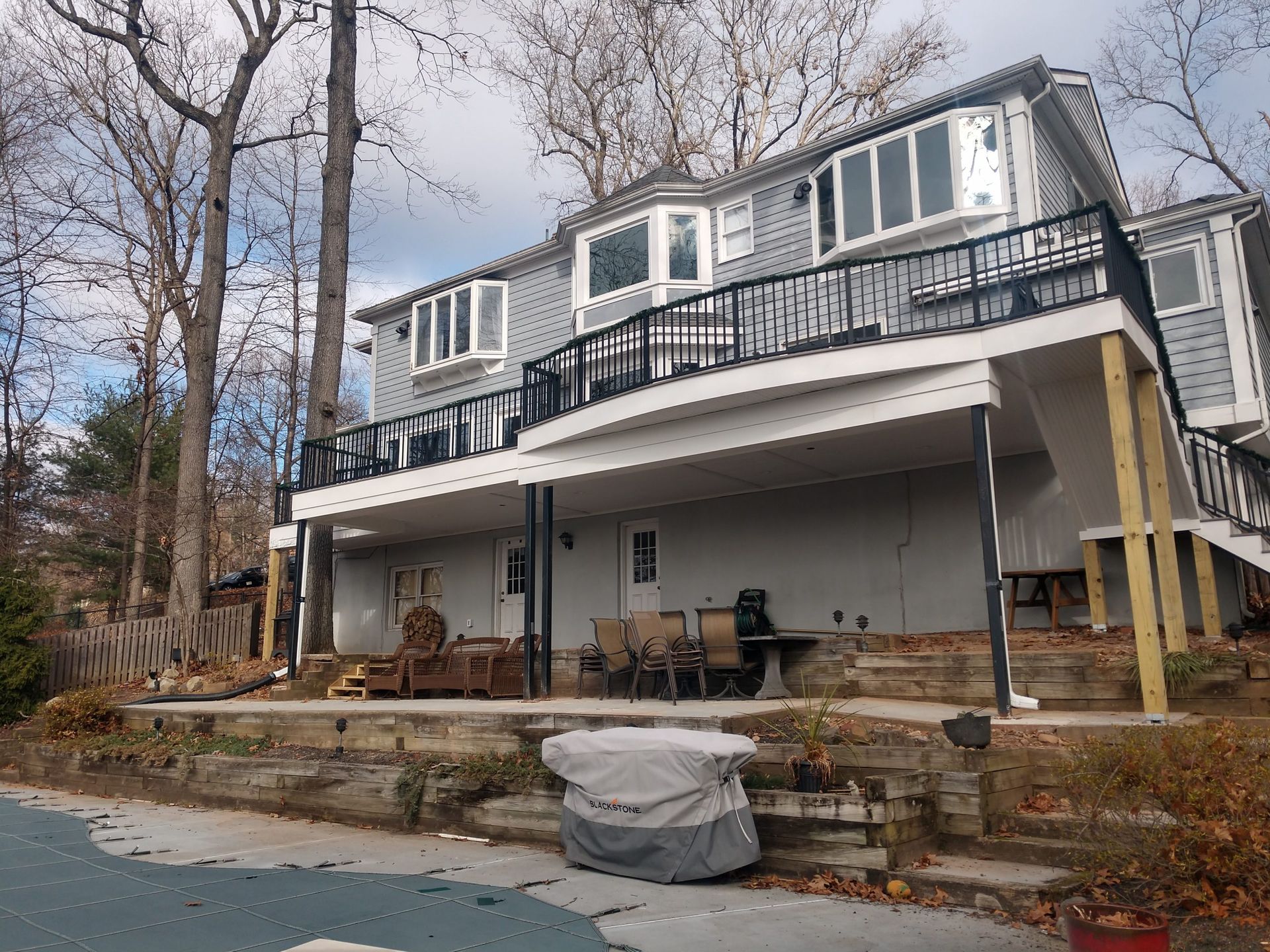 Elevated two-level deck with white posts, black railings, and covered lower patio area.