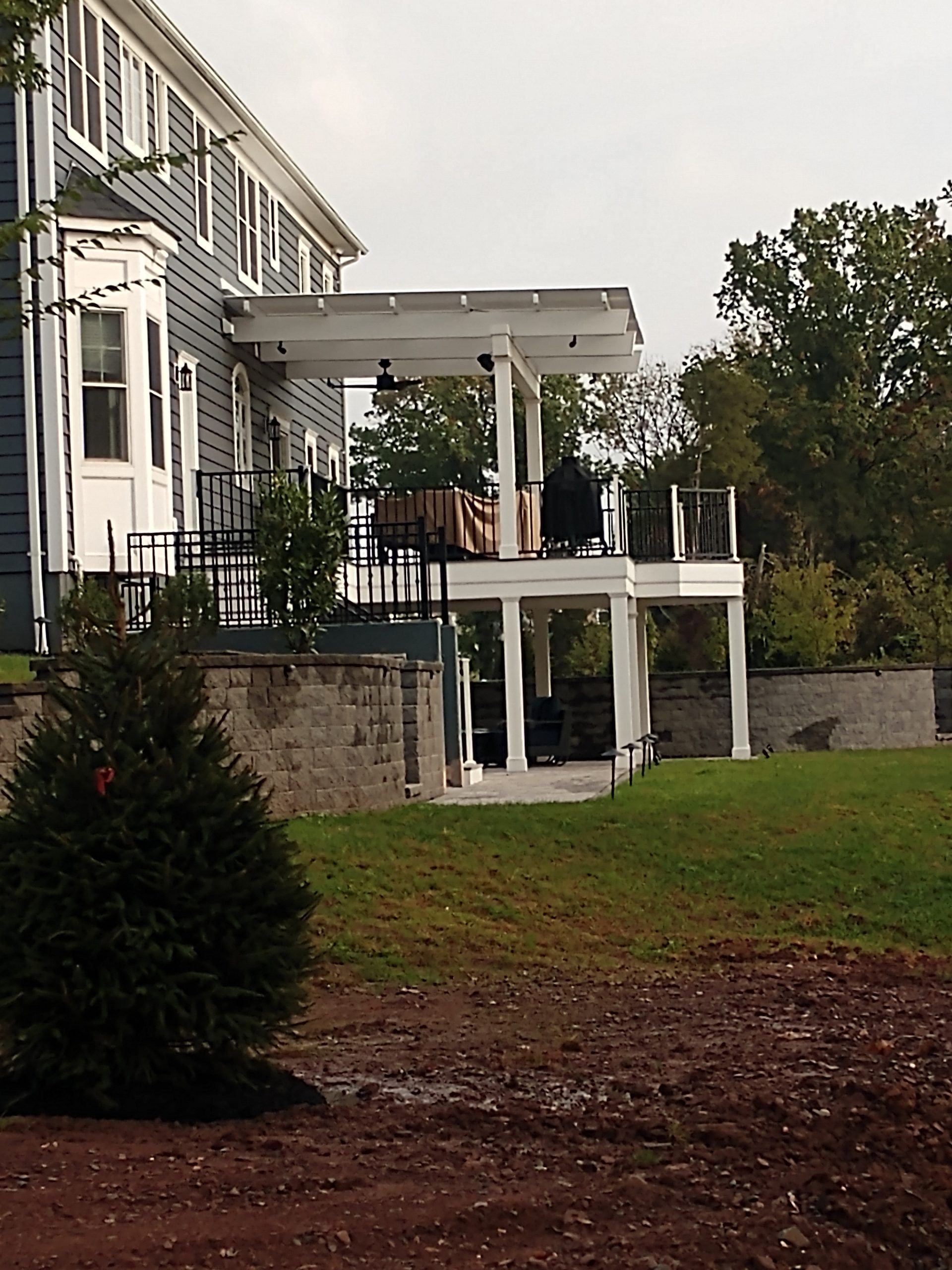 Modern home deck with white posts, black railings, and attached pergola roof.
