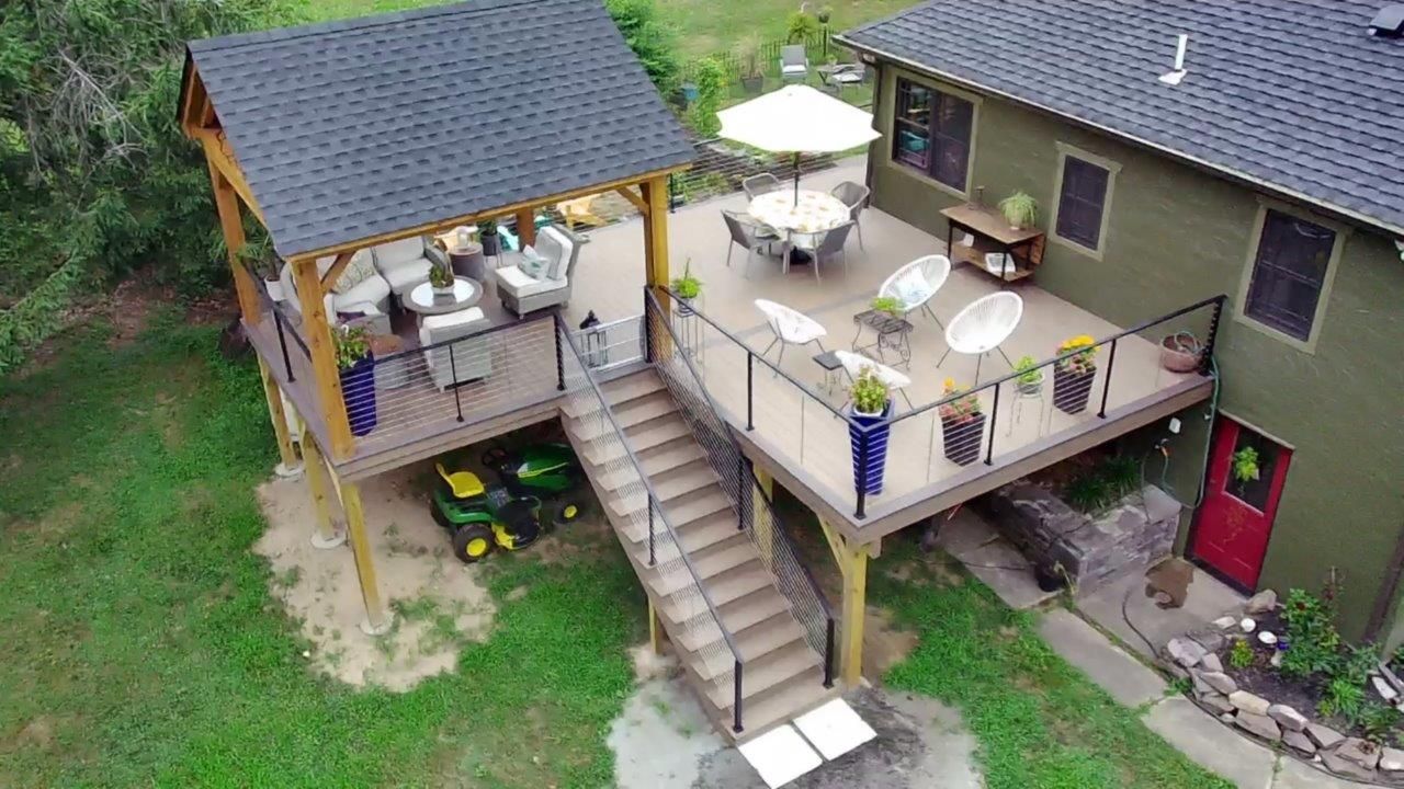 An aerial view of a house with a large deck and stairs leading up to it.