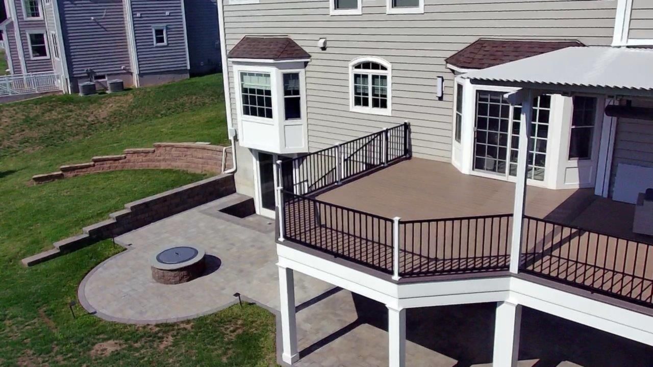 An aerial view of a house with a large deck and a fire pit.