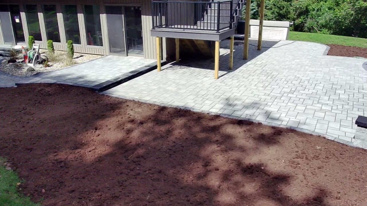 A patio with a deck in the backyard of a house.