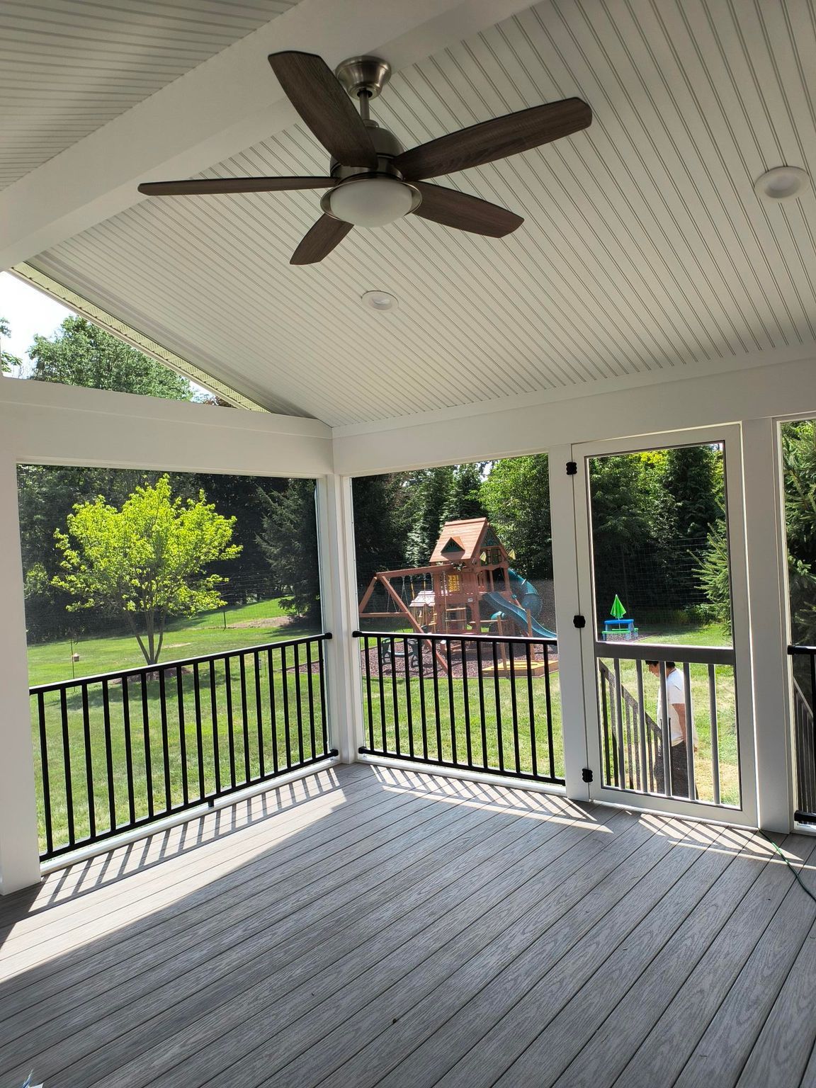 Interior view of screened porch with ceiling fan and composite decking by New Dimensions NJ