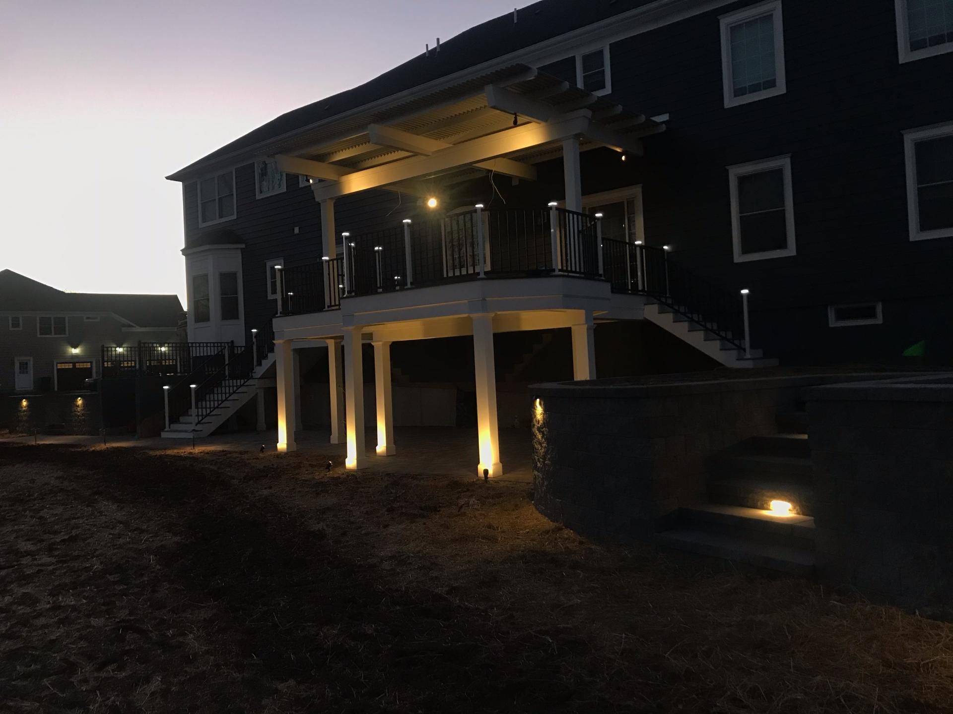 Deck with pergola lighting at dusk highlighting stairs, columns, and outdoor area.