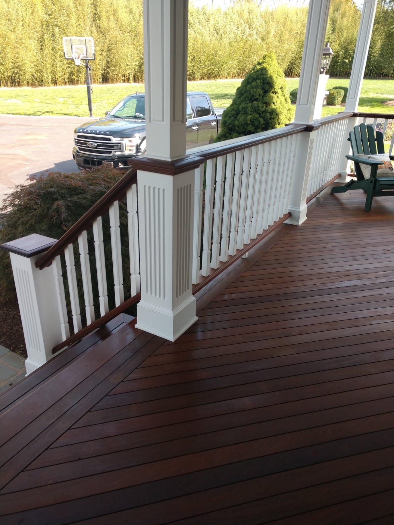A wooden deck with a white railing and a basketball hoop in the background.