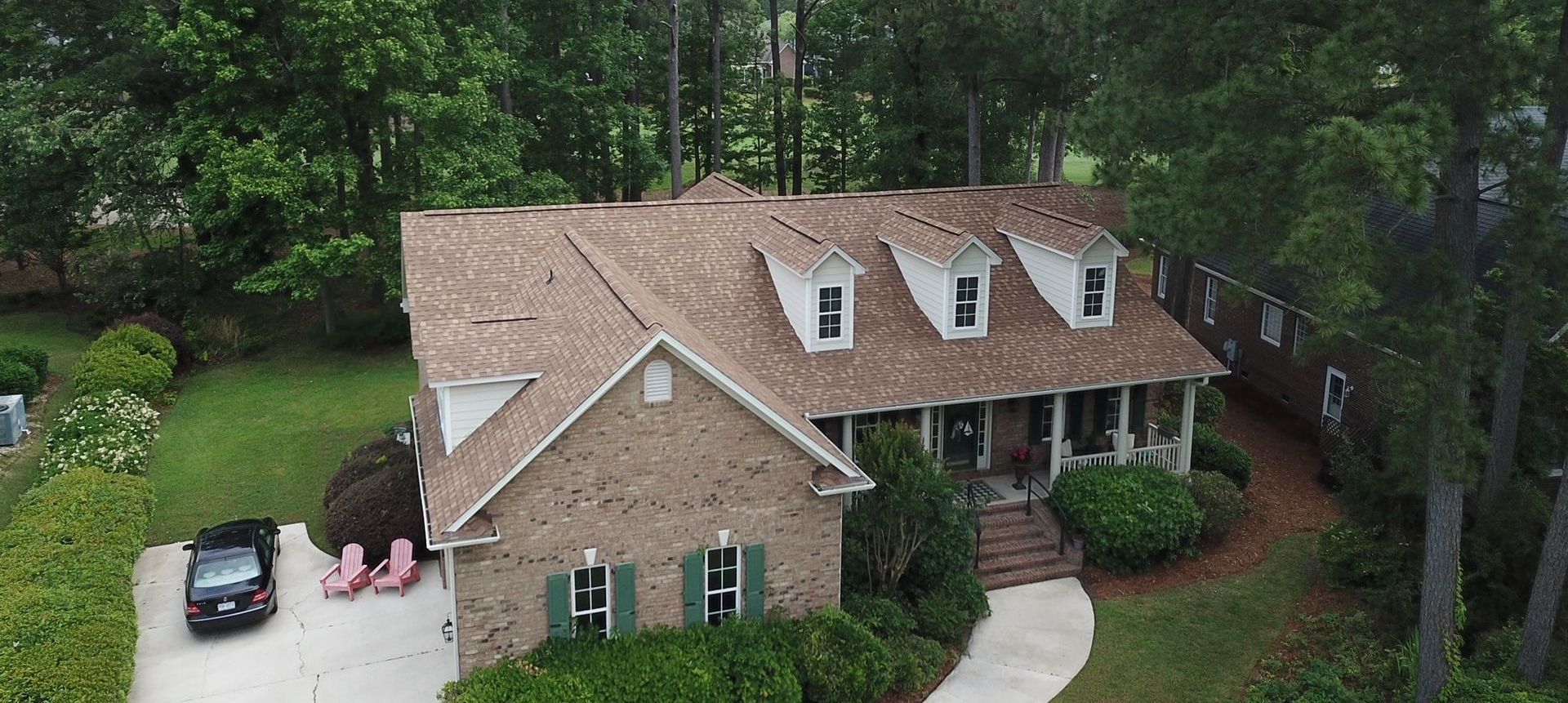 An aerial view of a brick house with a car parked in front of it.