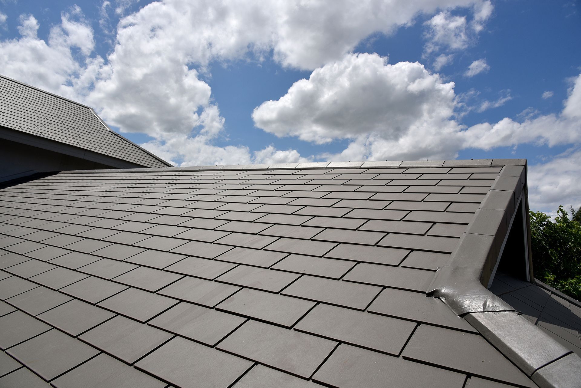 A slate roof with a blue sky and clouds in the background