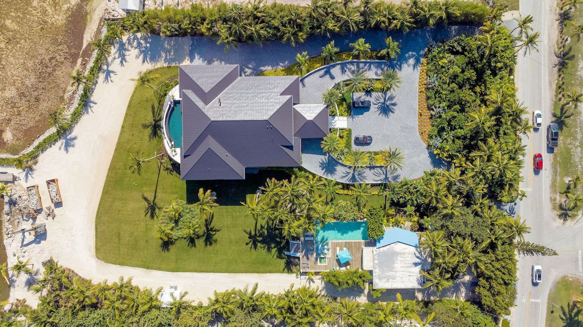 An aerial view of the The Oasis Guest House with a swimming pool and the Main House with palm trees around both. 