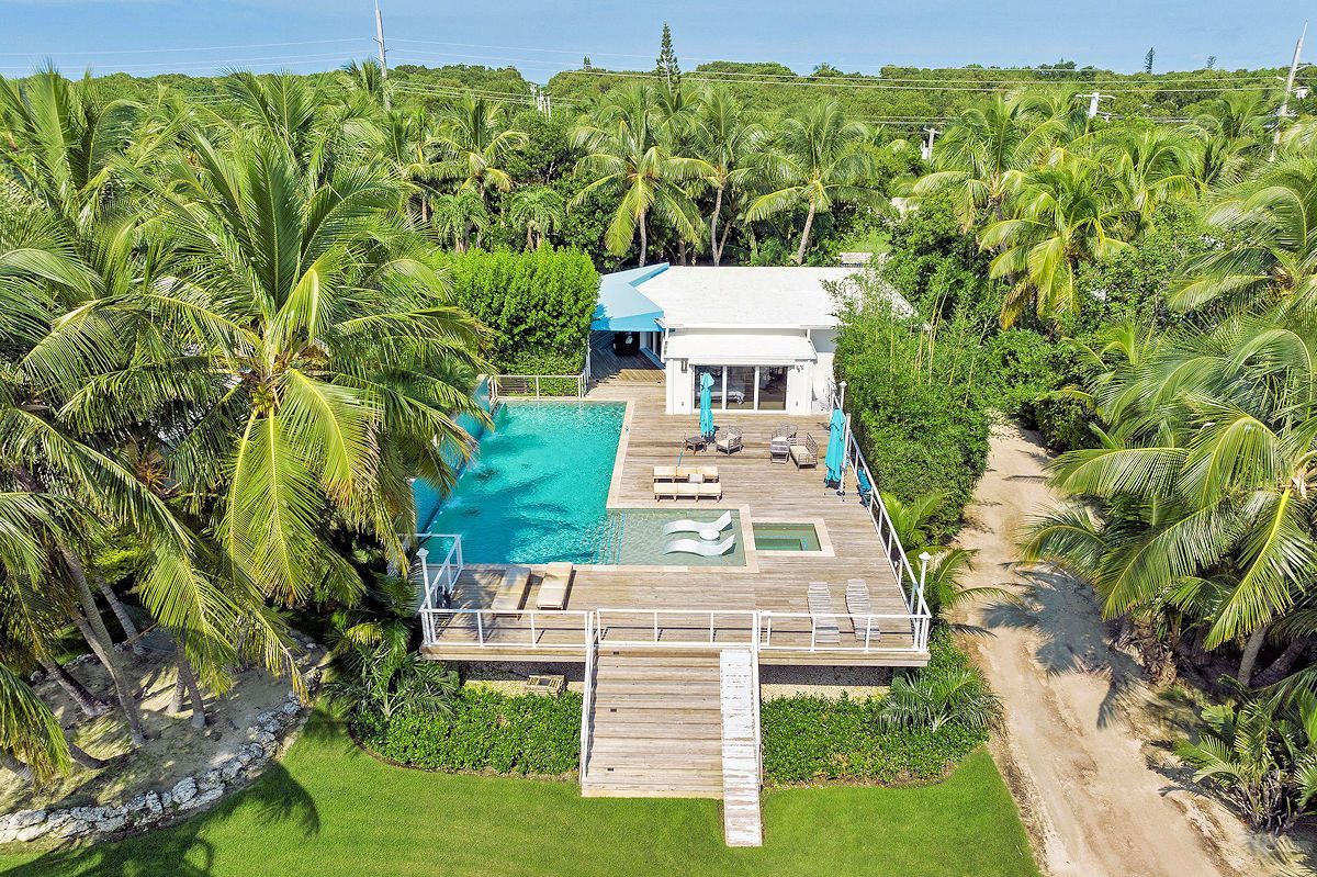 The Oasis Guest House, an aerial view of a house with a large swimming pool surrounded by palm trees .
