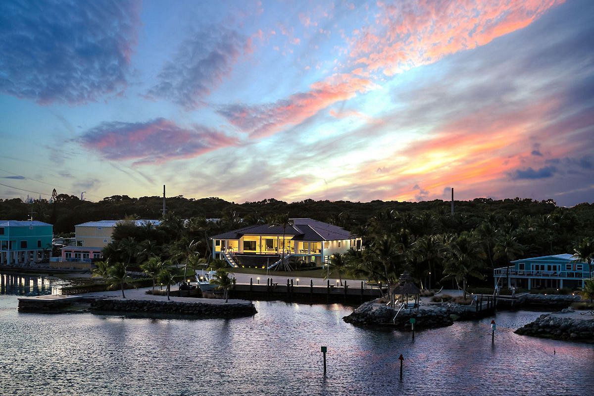 The Oasis, a sunset over a body of water with a house in the background .