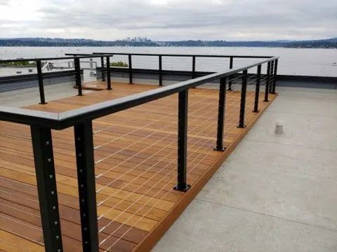 Rooftop deck with wood flooring and black railings overlooking the water