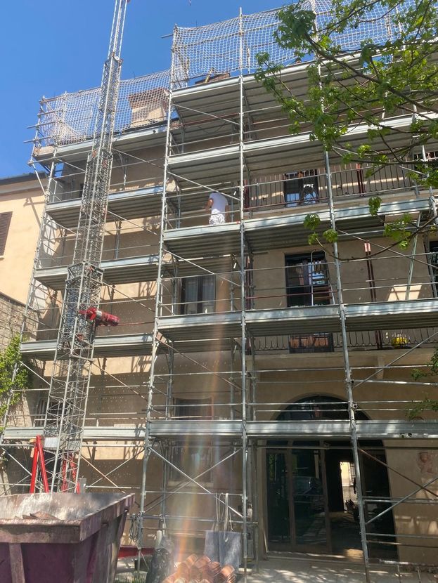 Impalcature che coprono la facciata di un edificio in ristrutturazione in una giornata di sole.