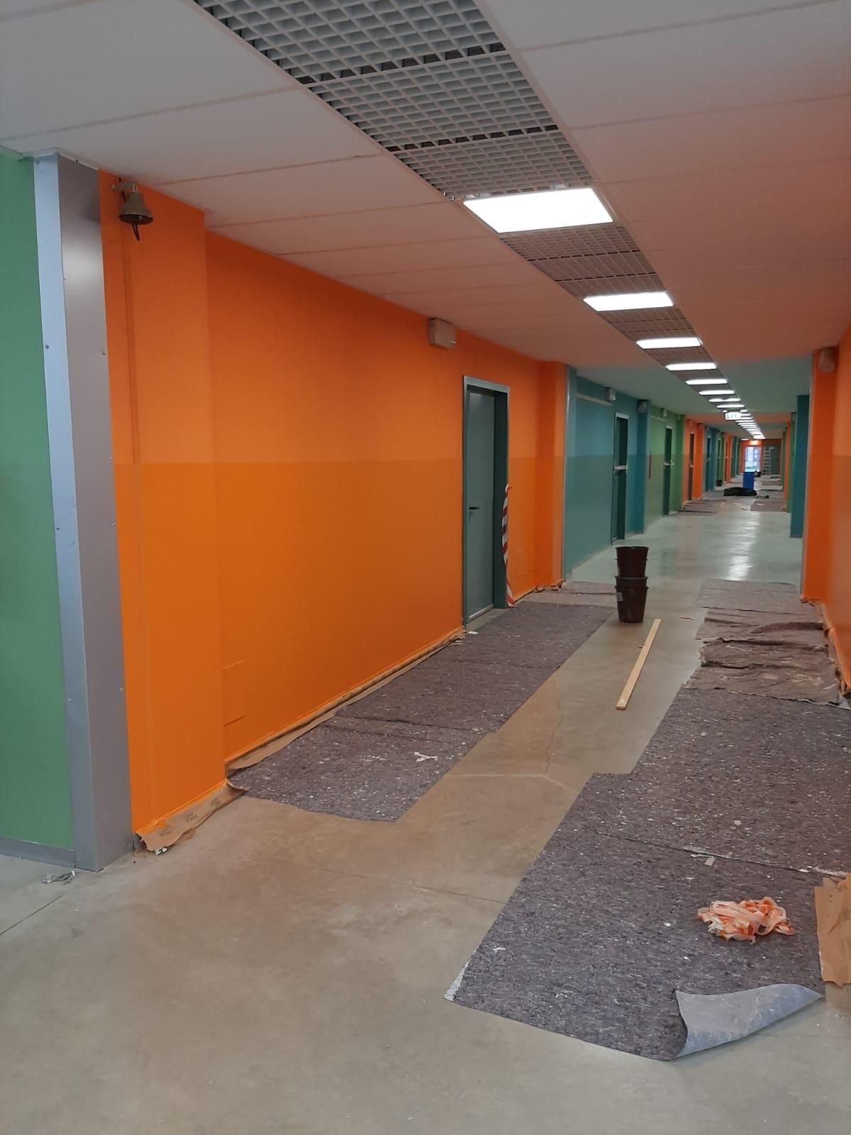 Corridoio arancione con porte, luci a soffitto e tappeti o moquette irregolari.