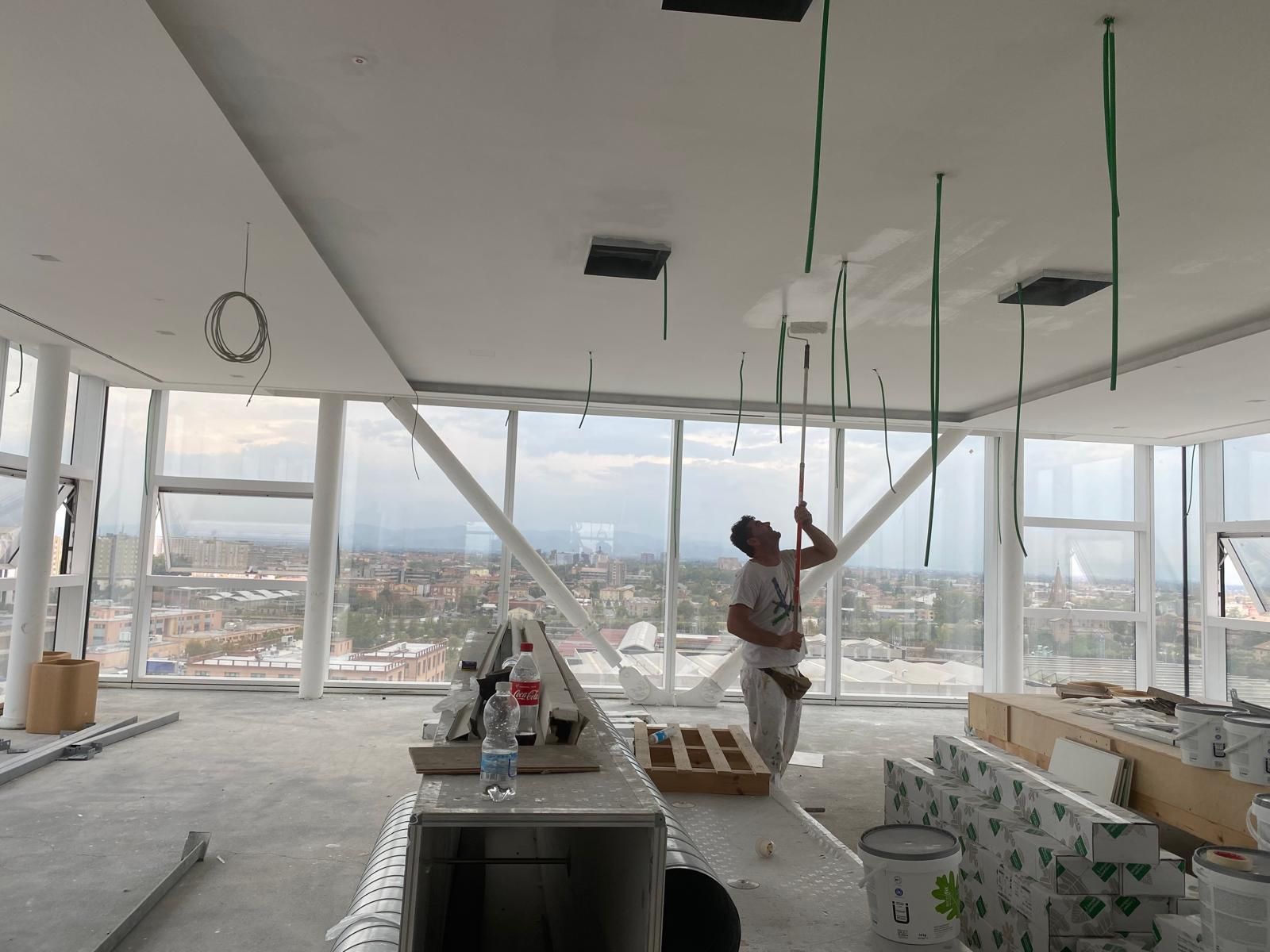 Operai che installano un soffitto in un luminoso appartamento in un grattacielo con vista sulla città e materiali edili sparsi tutt'intorno