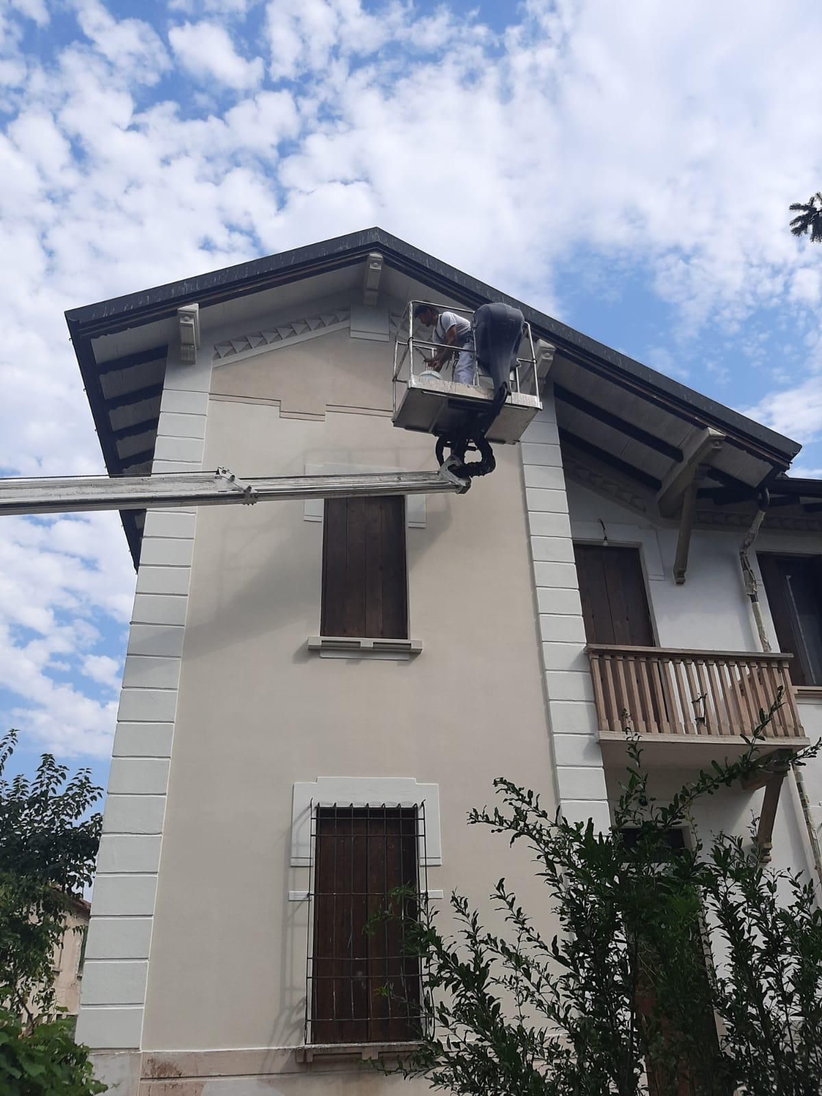Casa beige a due piani con balcone e palo della luce davanti, sotto un cielo nuvoloso