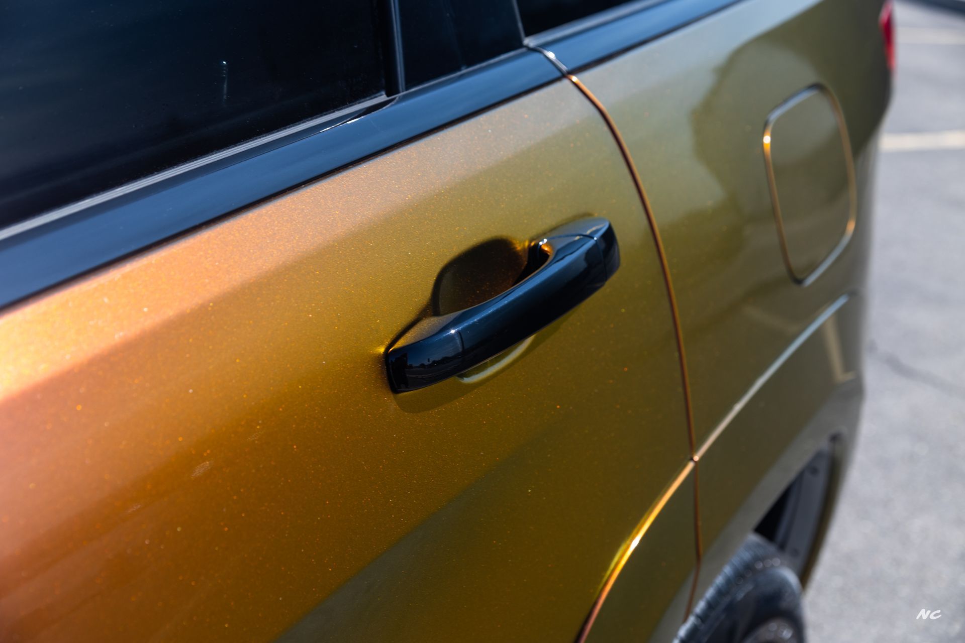 Close-up of a car door with iridescent gold paint and a black door handle.
