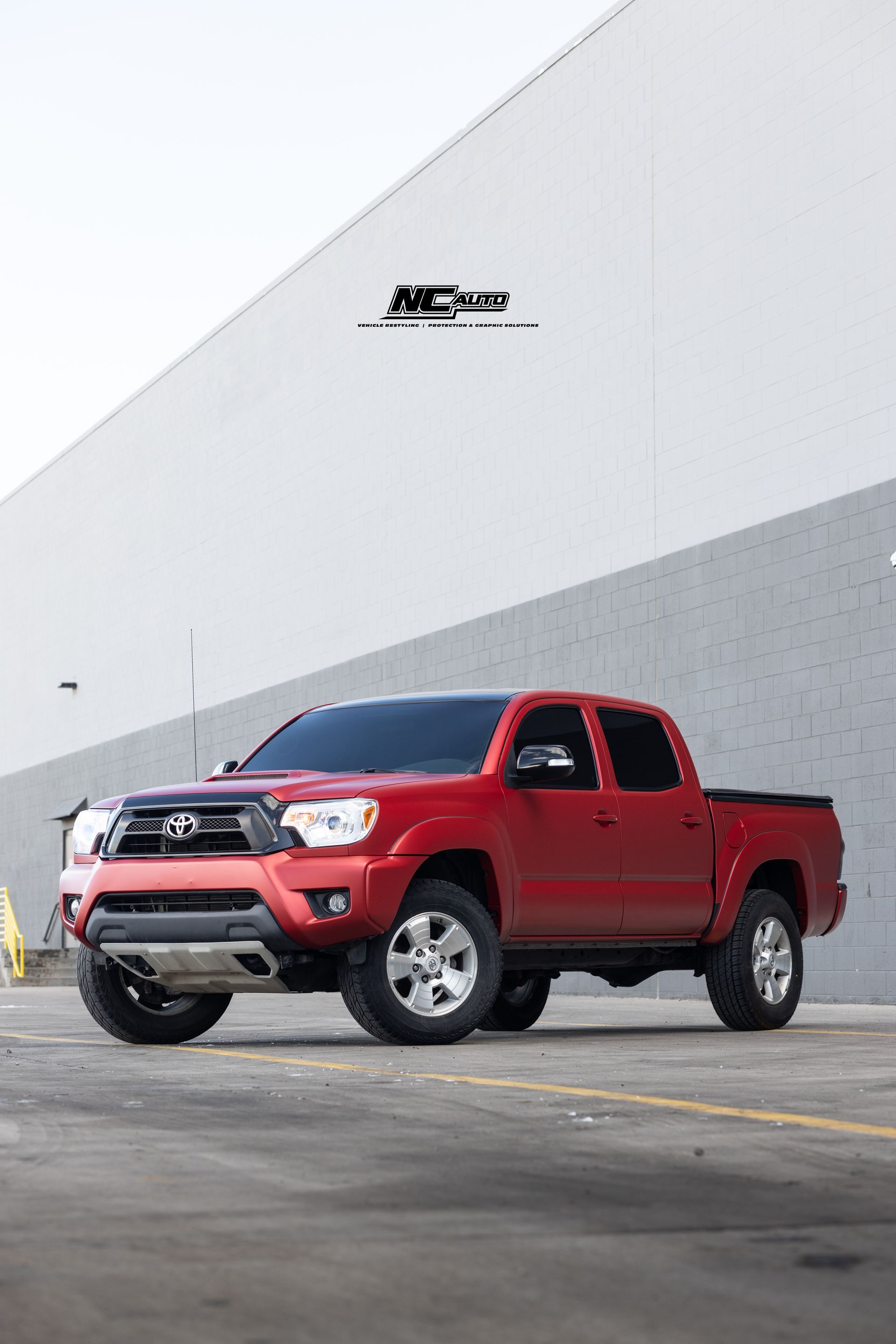 Red Toyota Tacoma truck parked in front of a white wall.