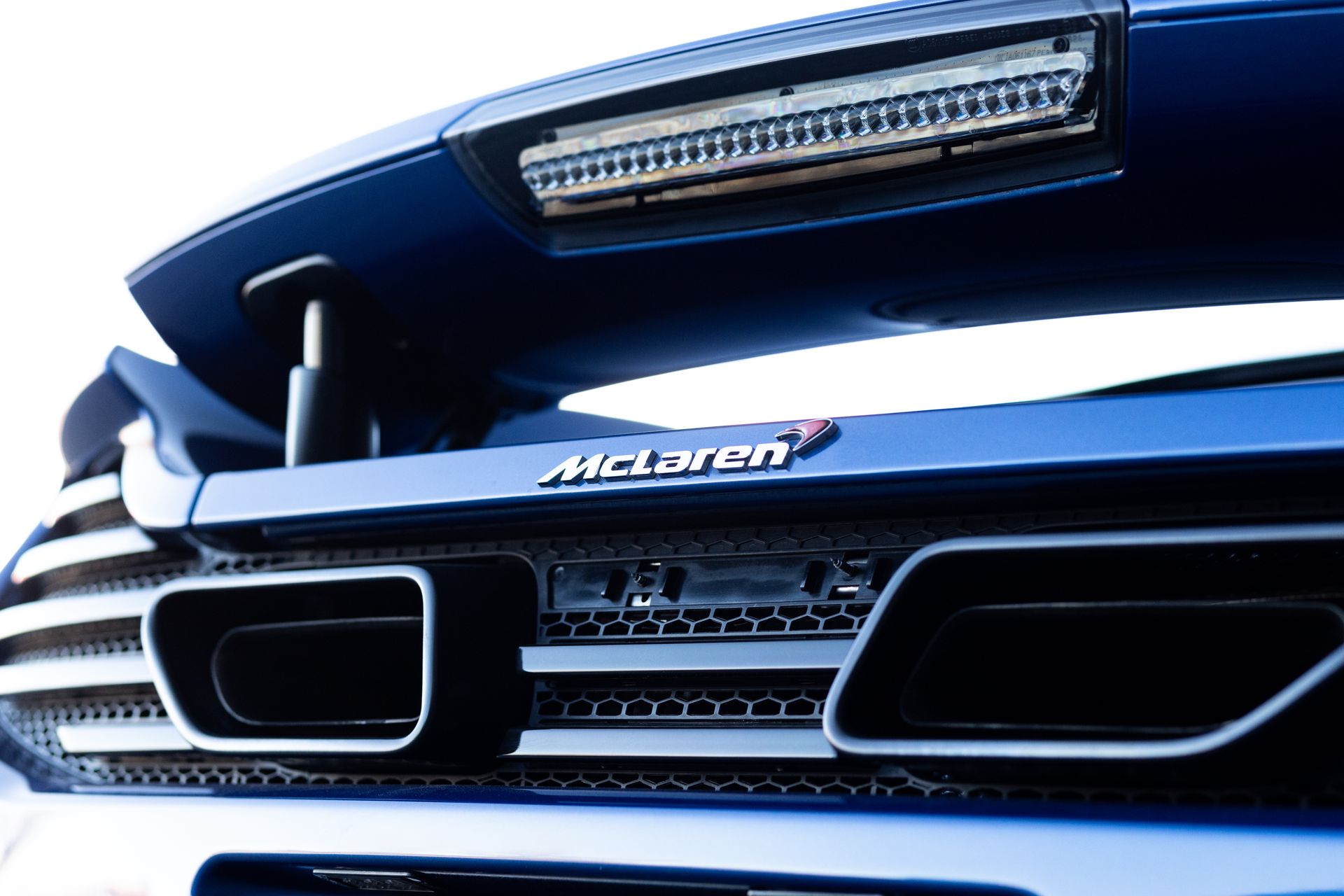 Blue McLaren sports car rear detail: exhaust pipes, grill, and 