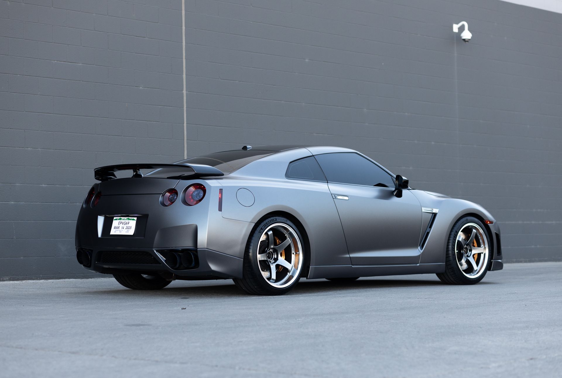Gray sports car parked next to a gray wall.