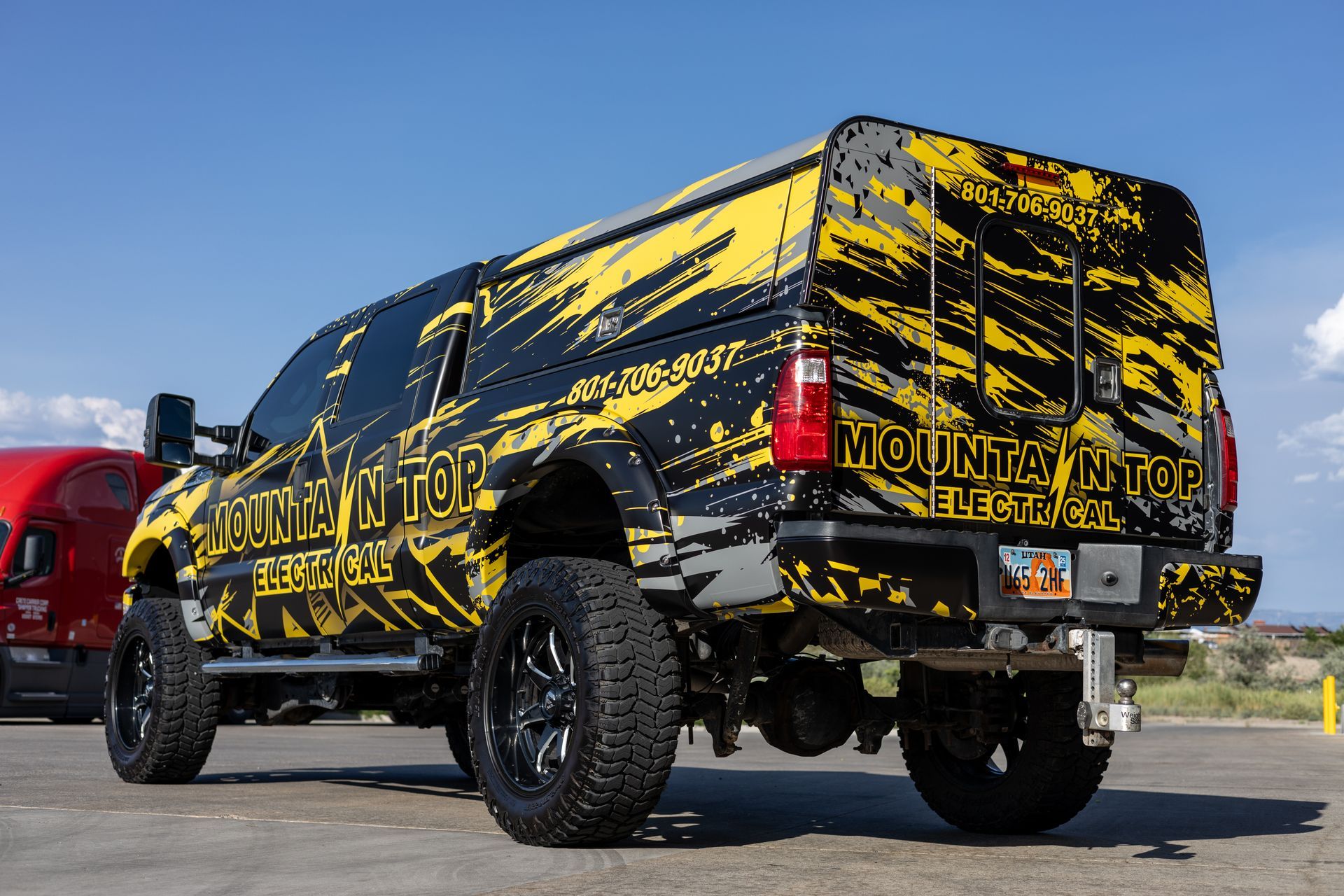 Modified truck with Mountain Top Electrical branding, yellow and black design. Utah license plate.