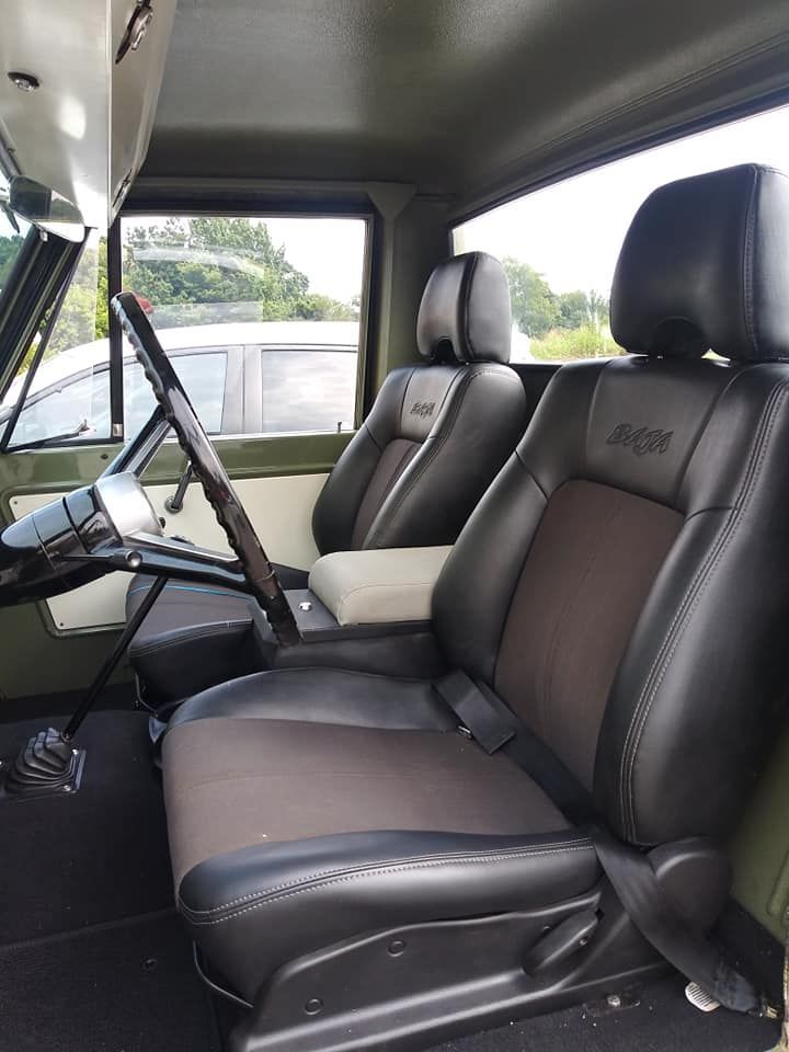 Interior of a vehicle featuring black bucket seats with custom stitching, a steering wheel, and a center console.